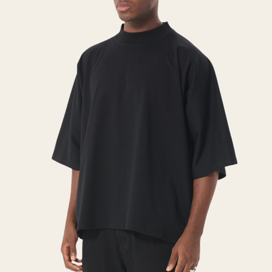 Person wearing a black oversized t-shirt on a plain background